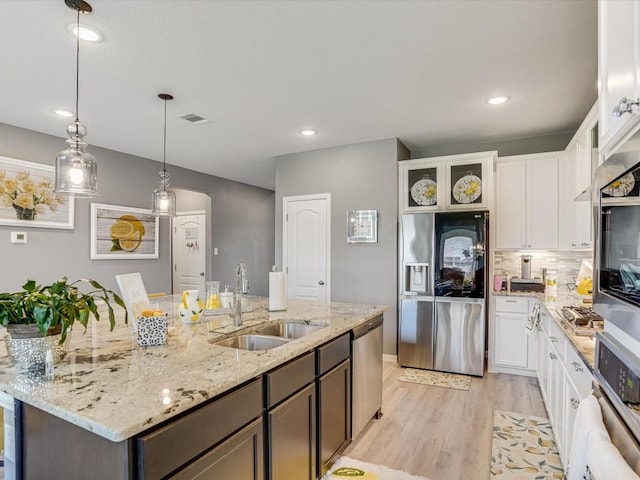 kitchen with a sink, visible vents, white cabinets, appliances with stainless steel finishes, and light wood-type flooring