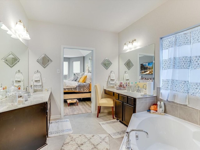 ensuite bathroom with tile patterned floors, a sink, a bath, and connected bathroom