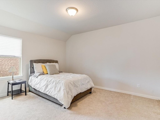 bedroom with light carpet, baseboards, and lofted ceiling