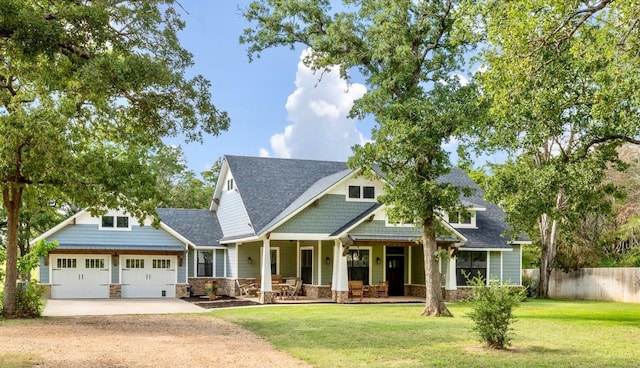 craftsman inspired home with fence, a garage, stone siding, driveway, and a front lawn