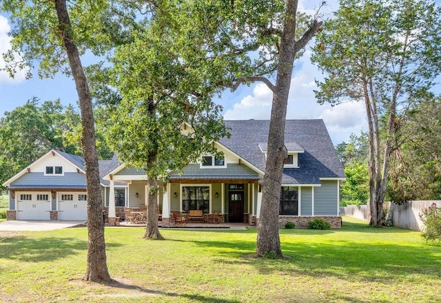 craftsman-style house featuring roof with shingles, a porch, fence, a garage, and a front lawn