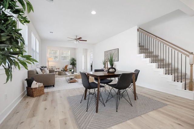 dining space with light wood-type flooring, baseboards, and stairway