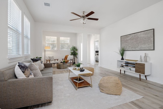 living room featuring baseboards, visible vents, ceiling fan, and wood finished floors