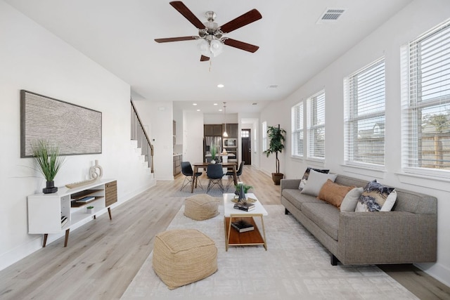 living room featuring light wood-style flooring, stairway, and baseboards