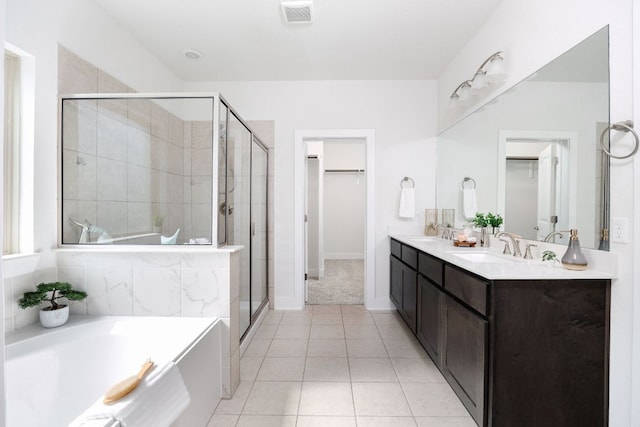 bathroom featuring a walk in closet, a garden tub, visible vents, a sink, and a shower stall