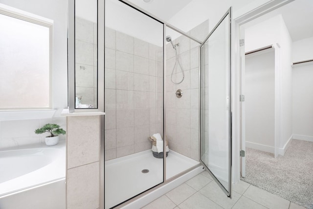 bathroom with a stall shower, tile patterned flooring, baseboards, and a garden tub