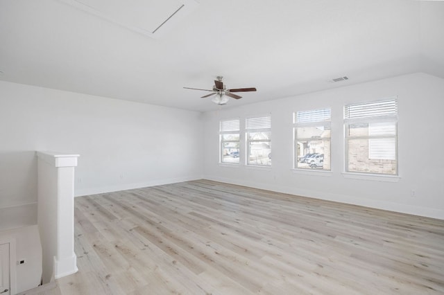 empty room featuring light wood finished floors, visible vents, vaulted ceiling, ceiling fan, and baseboards