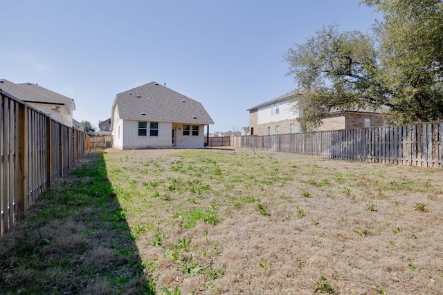 back of house with a fenced backyard and a yard