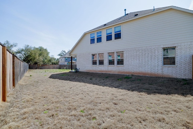 back of property featuring brick siding and a fenced backyard