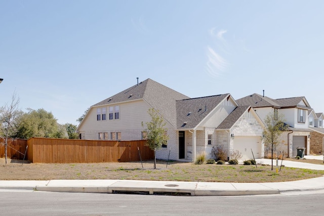 view of front of property featuring a garage, driveway, brick siding, and fence