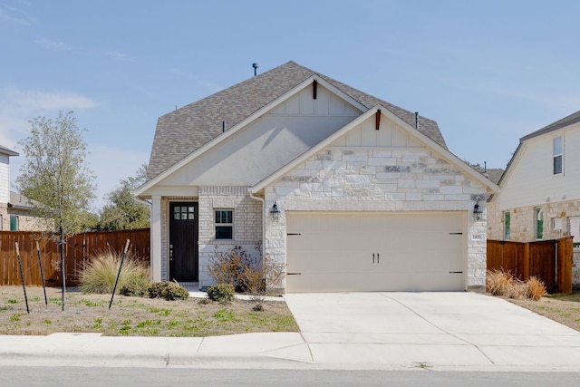 view of front of home with a garage, driveway, stone siding, fence, and board and batten siding