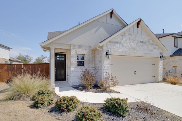 view of front of property with a garage, fence, stone siding, concrete driveway, and board and batten siding