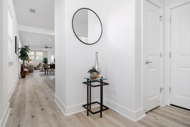 hallway with light wood-type flooring, baseboards, and visible vents