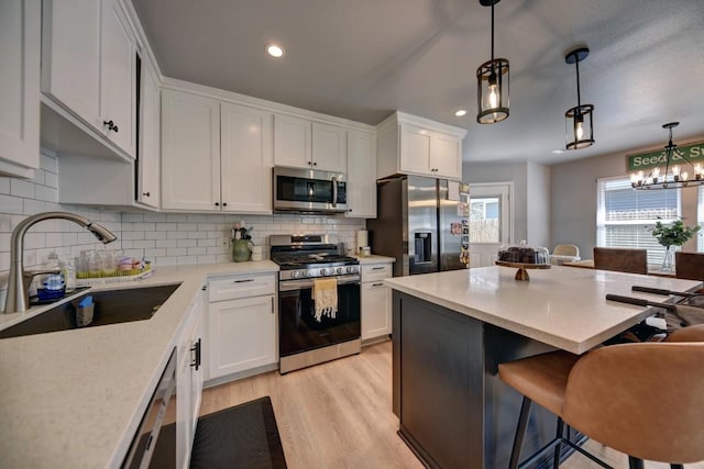 kitchen with stainless steel appliances, white cabinetry, a sink, and a breakfast bar area