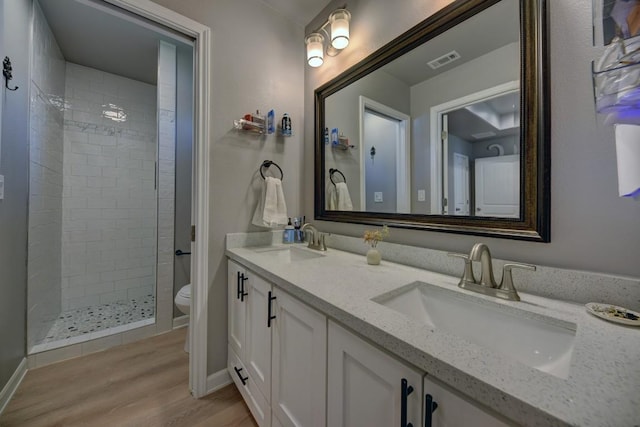 full bath with toilet, visible vents, a tile shower, and a sink