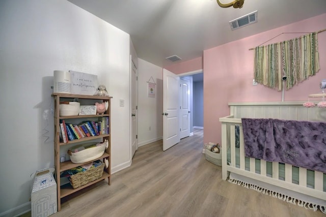 bedroom with baseboards, visible vents, and wood finished floors