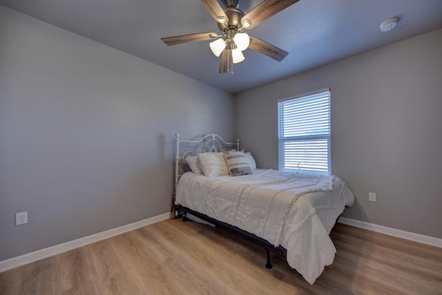 bedroom with a ceiling fan, baseboards, and wood finished floors