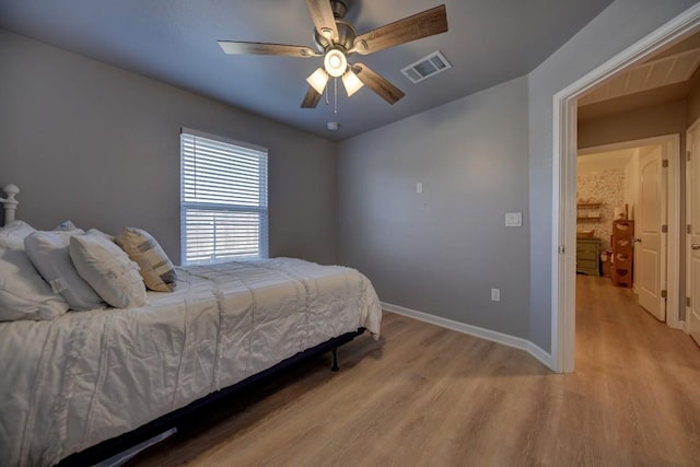 bedroom with light wood-style flooring, a ceiling fan, visible vents, and baseboards