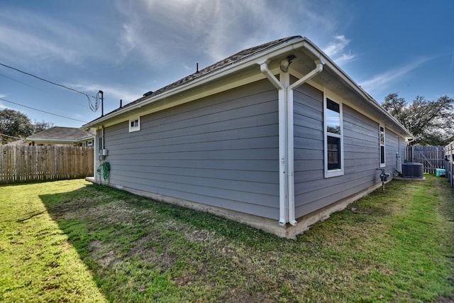 view of side of property featuring cooling unit, a yard, and fence