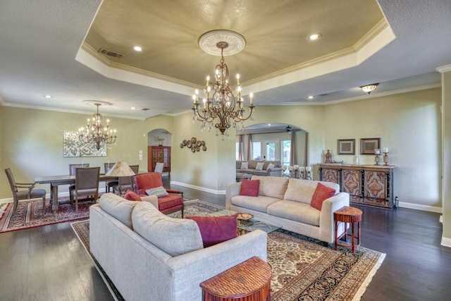 living room with arched walkways, visible vents, dark wood finished floors, and a tray ceiling