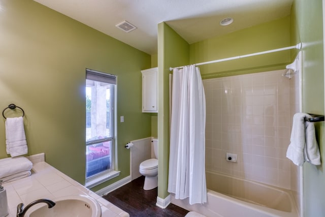 bathroom featuring visible vents, toilet, shower / tub combo, a sink, and baseboards