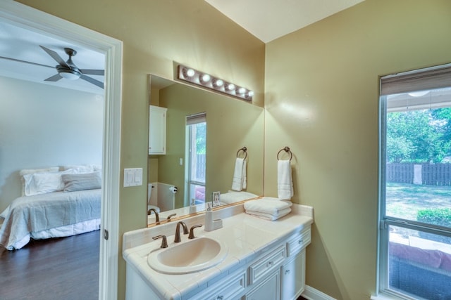 bathroom with wood finished floors, vanity, baseboards, a ceiling fan, and ensuite bath