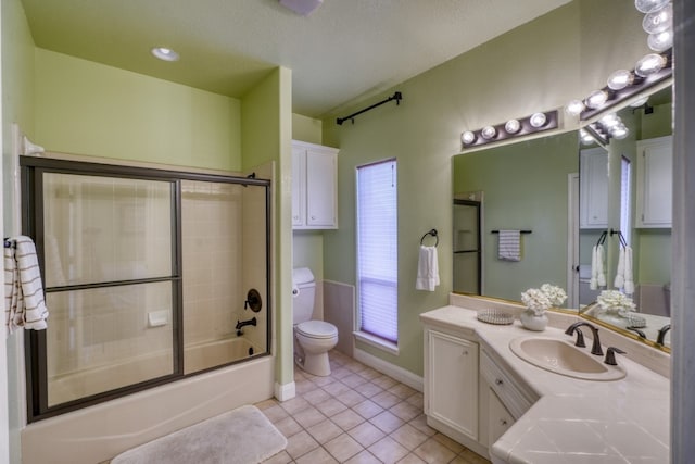 bathroom featuring tile patterned flooring, toilet, bath / shower combo with glass door, vanity, and baseboards