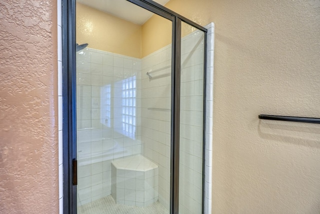 full bathroom with a textured wall and a shower stall