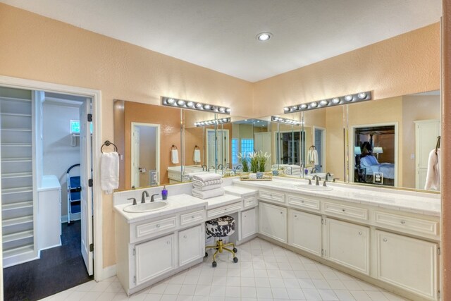 606 Free Rein, Horseshoe Bay, TX 78657 - ensuite bathroom featuring double vanity, tile patterned flooring, recessed lighting, and a walk in closet
