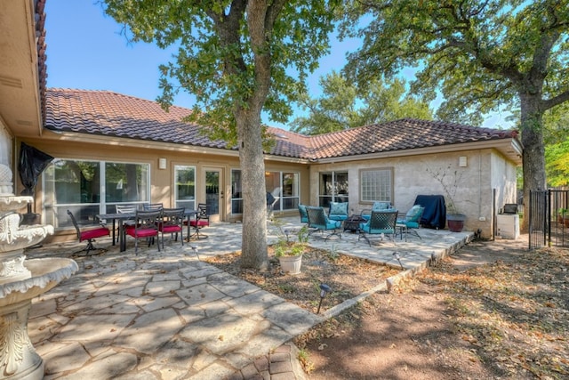 rear view of house with stucco siding, a tiled roof, and a patio