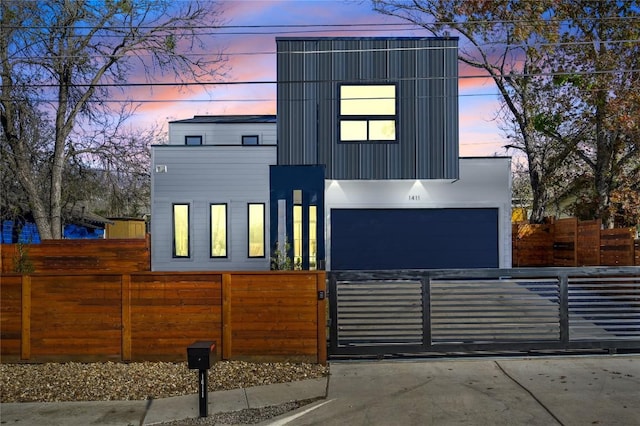 modern home with driveway, a fenced front yard, and a gate