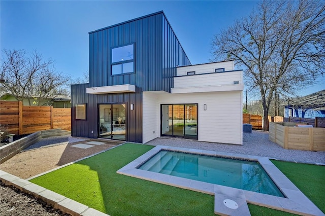 back of house with a fenced backyard, a lawn, board and batten siding, a swimming pool, and a patio area