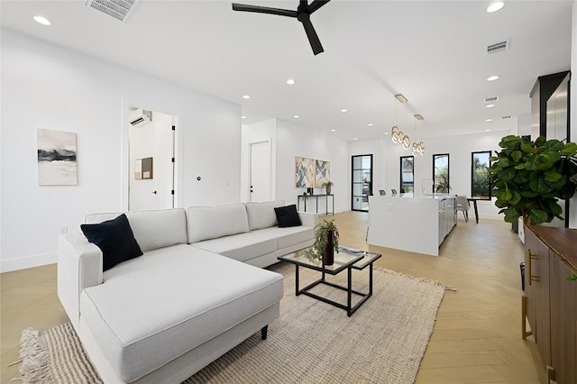 living room featuring baseboards, an AC wall unit, visible vents, and recessed lighting