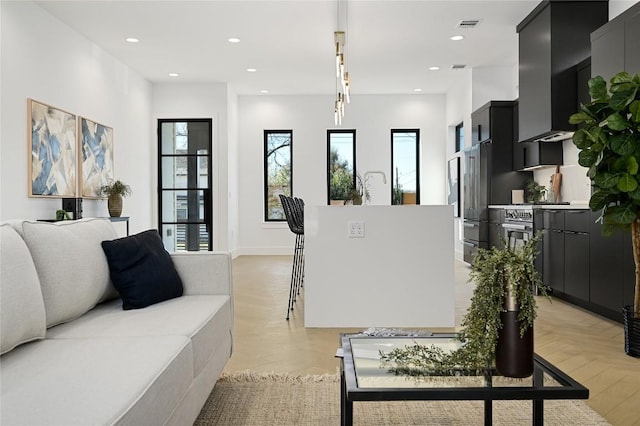 kitchen featuring light countertops, dark cabinetry, an island with sink, and recessed lighting