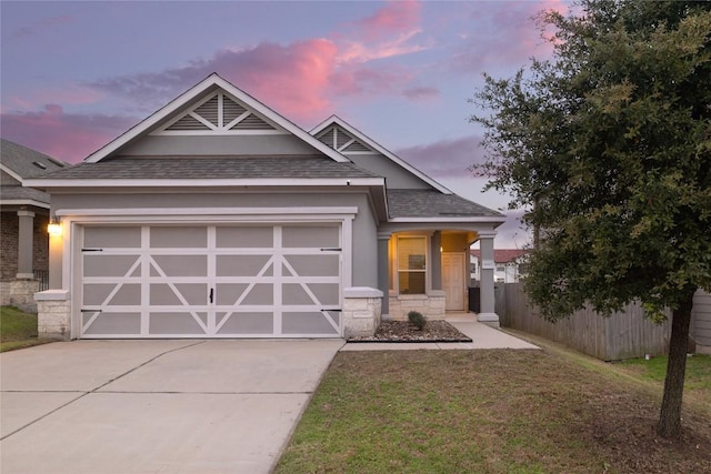 craftsman-style home featuring a garage, a shingled roof, concrete driveway, fence, and a front yard