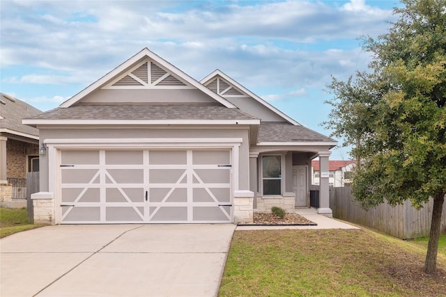 craftsman inspired home with roof with shingles, fence, a garage, driveway, and a front lawn