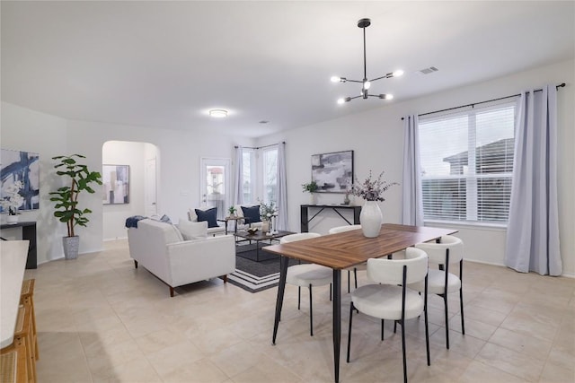 dining room with arched walkways, visible vents, and an inviting chandelier