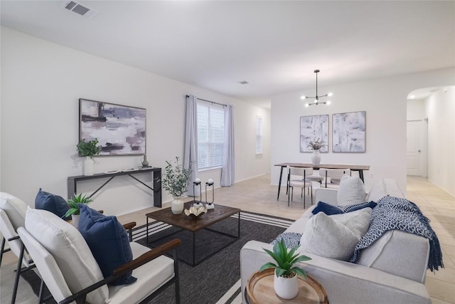 living room featuring arched walkways, visible vents, a notable chandelier, and baseboards