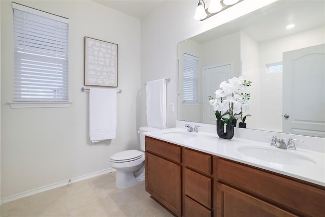 bathroom featuring toilet, double vanity, baseboards, and a sink