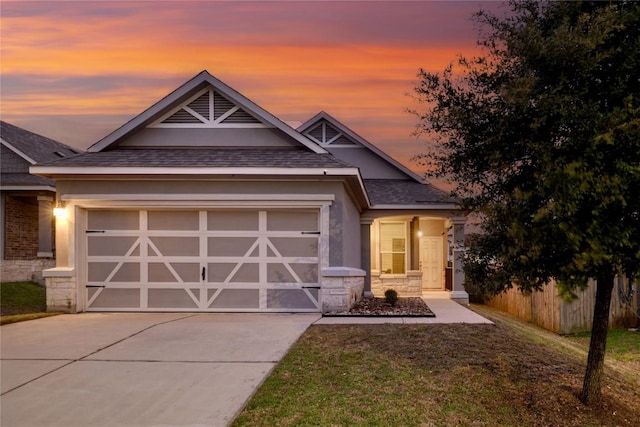 craftsman house with a garage, stone siding, driveway, and stucco siding