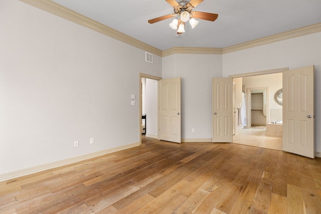 spare room featuring light wood-type flooring, visible vents, ornamental molding, and baseboards