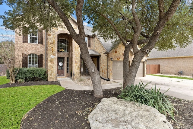 view of front of house featuring driveway, stone siding, fence, and brick siding