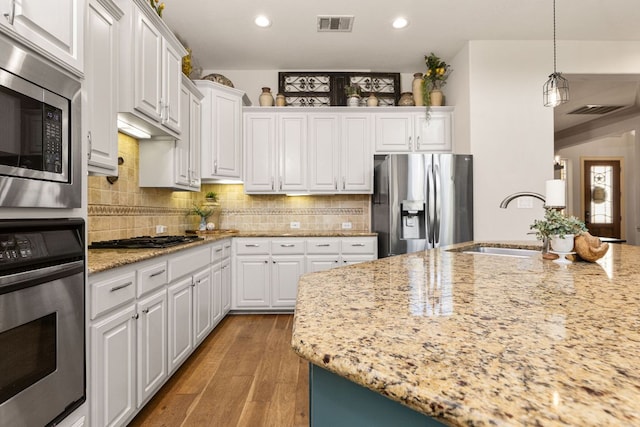 kitchen with stainless steel appliances, white cabinetry, backsplash, and wood finished floors