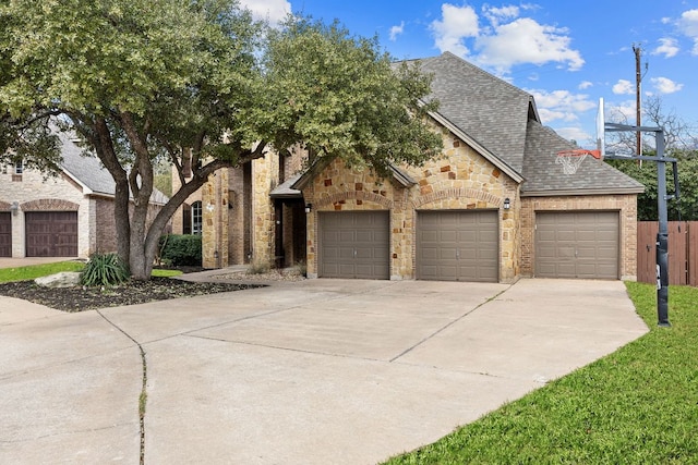 view of front of house featuring driveway, a garage, stone siding, roof with shingles, and fence