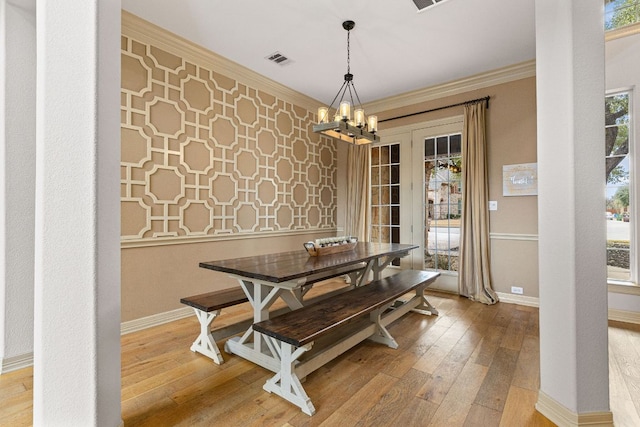 dining room with wood-type flooring, visible vents, baseboards, and ornamental molding