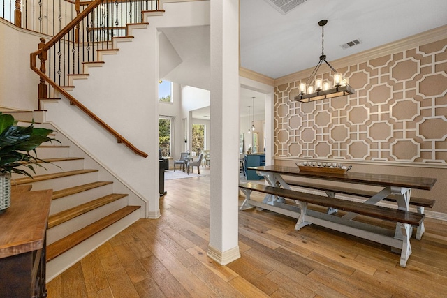 dining room featuring an inviting chandelier, wood-type flooring, visible vents, and crown molding