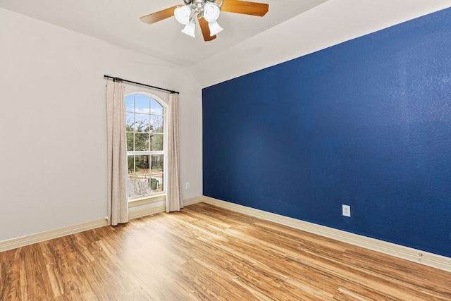 unfurnished room with ceiling fan, baseboards, vaulted ceiling, and wood finished floors