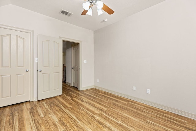 unfurnished bedroom with visible vents, light wood-style flooring, vaulted ceiling, ceiling fan, and baseboards