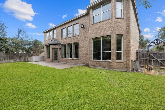 back of property with a patio, a yard, a fenced backyard, and brick siding