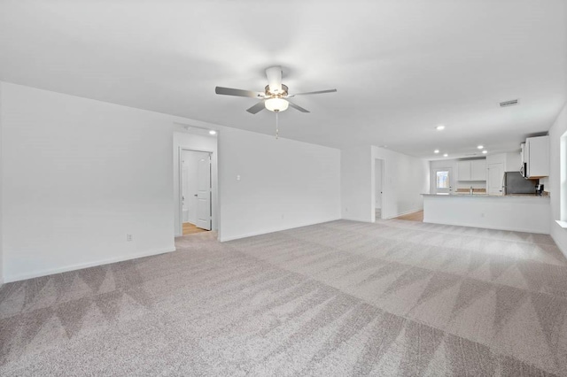 unfurnished living room with recessed lighting, light colored carpet, visible vents, ceiling fan, and baseboards